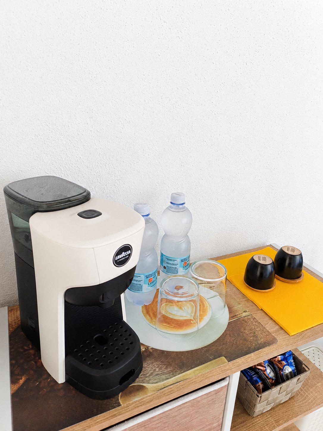 Angolo caffè con macchina Lavazza, acqua, bicchieri e tazze